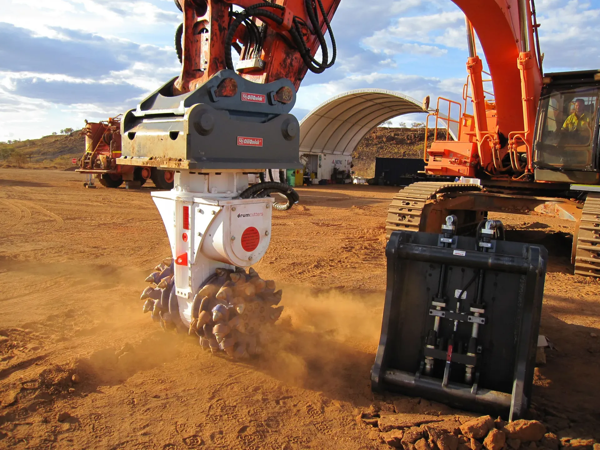 OilQuick coupler with drum cutter attachment on a Hitachi excavator at an Australian mine site at golden hour