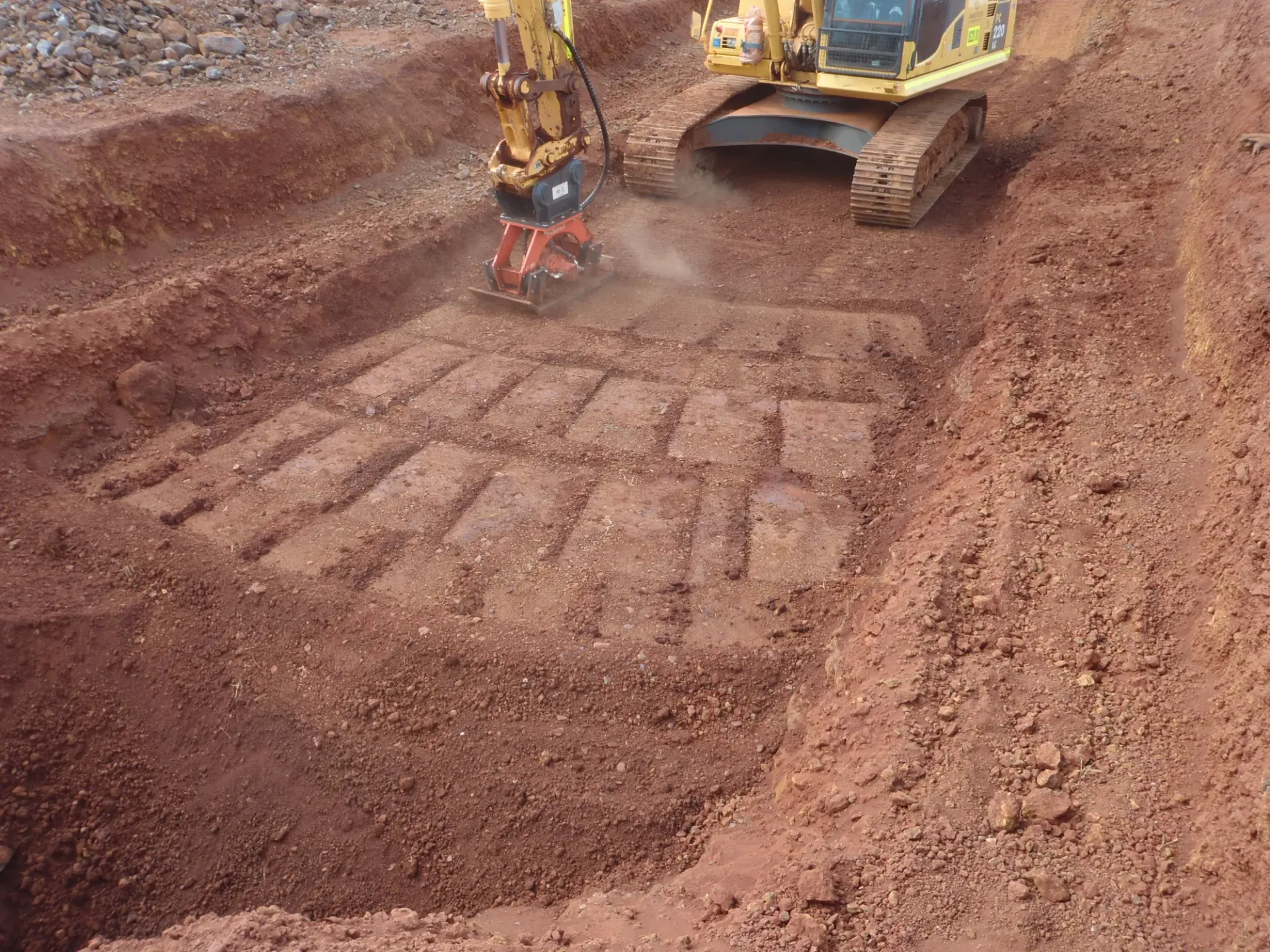 PneuVibe boom-mounted compactor finishing a trench floor in red Pilbara earth